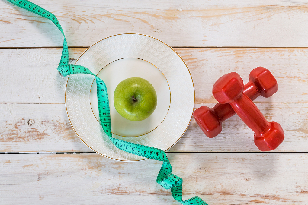 fitness concept with dumbbells and measuring tape